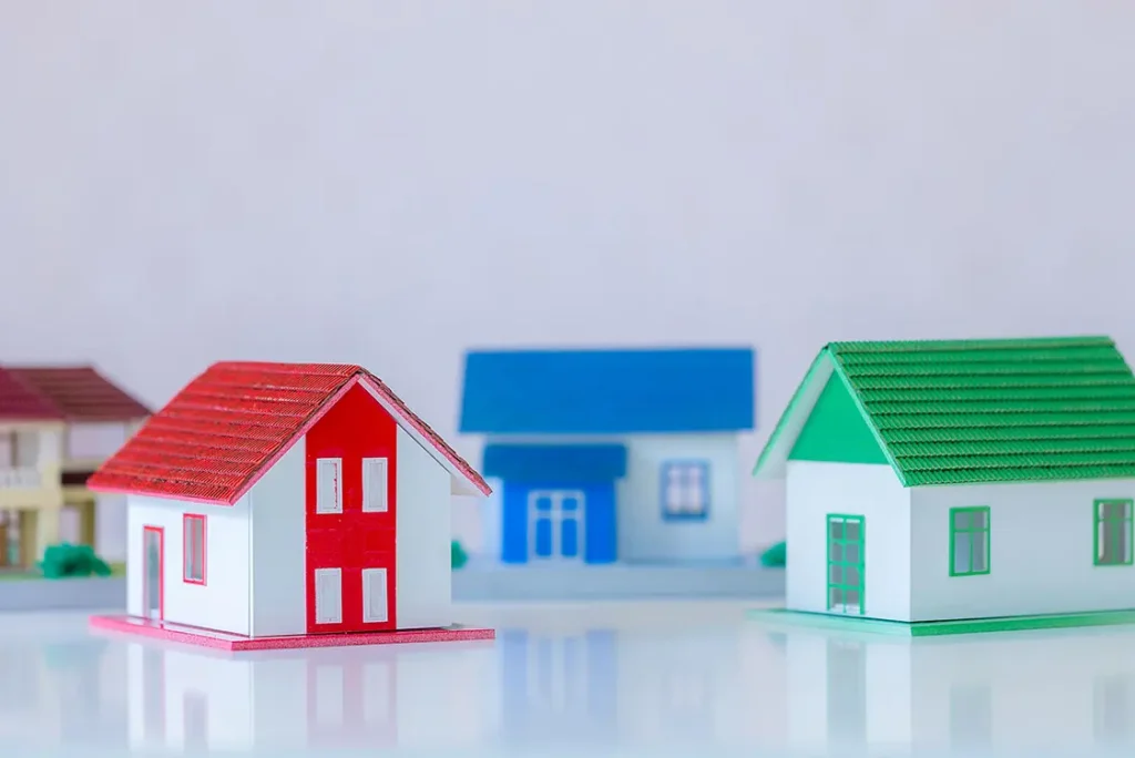 Casas de brinquedo, nas cores vermelha, verde e azul, sobre uma mesa.