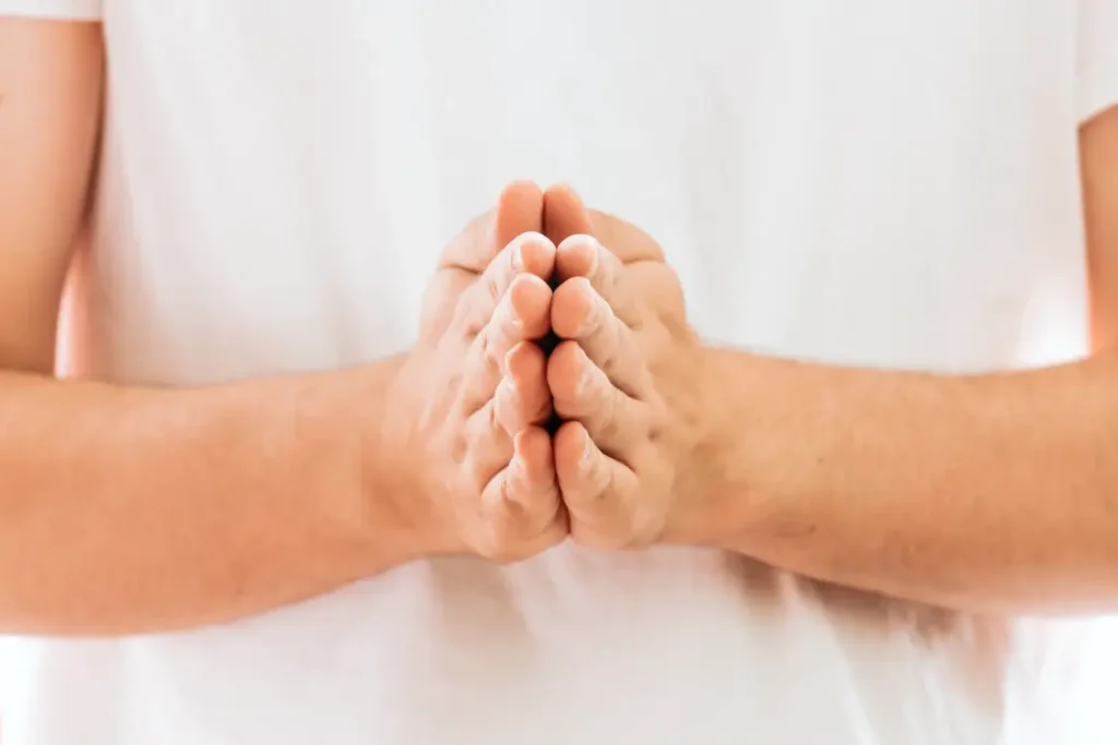 Homem branco com as mãos juntas