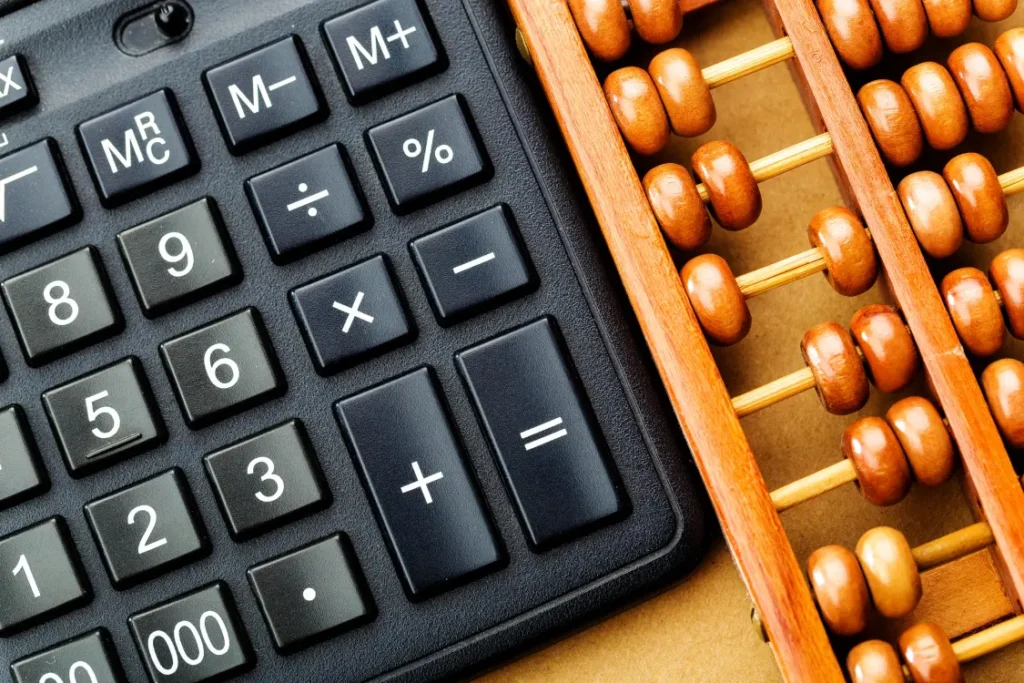 imagem vista de cima de uma calculadora ao lado de um ábaco