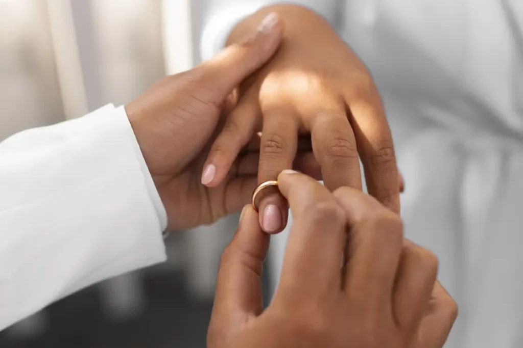 Mãos masculinas colocando uma aliança em uma mão feminina